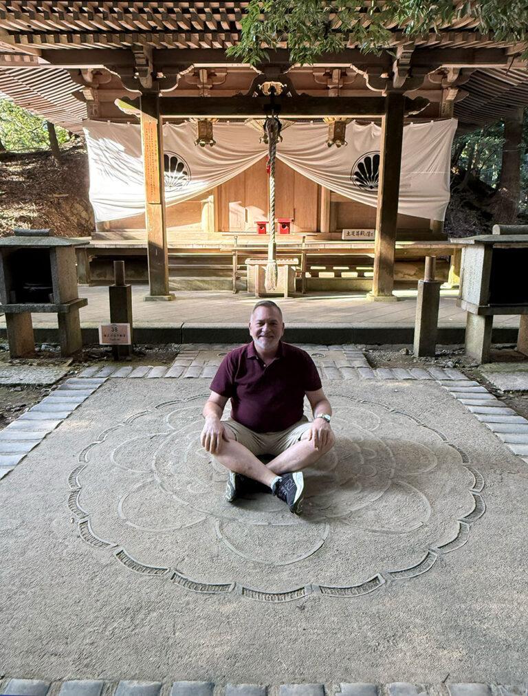 Photo of Brian Brunius sitting on the mandala on the ground outside the Fudo temple on Mount Kurama.
