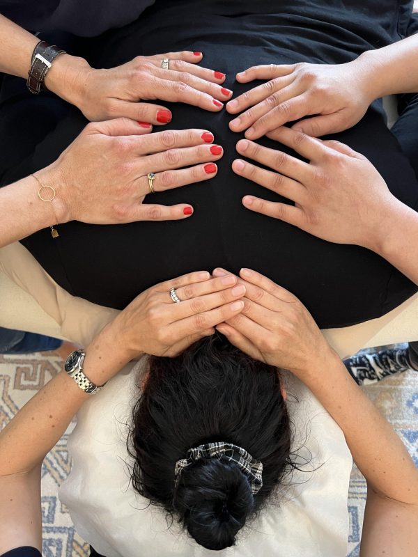 Photo of a students' hands delivering a Reiki treatment to another student in a class at the NYC Reiki Center in New York City